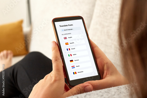 Close up photo of a girl on a sofa using language translator app with mobile smartphone.