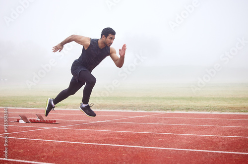 Outdoor, exercise and man running at track for fitness, sports and training for competition. Mist, fog and Asian male athlete with speed at athletics field for cardio, workout and practice for race