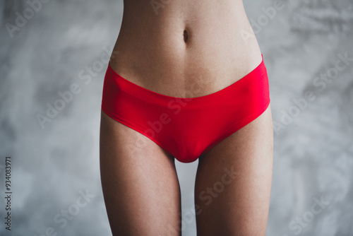 No filter photo skinny girl wearing red underwear showing her imperfections skin isolated on gray color studio background