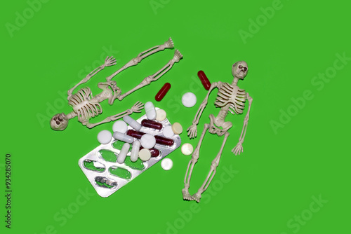 Skeletons lying next to pills and capsules. Danger of drug overdose, medication use, pills. Health risk from uncontrolled drug use.