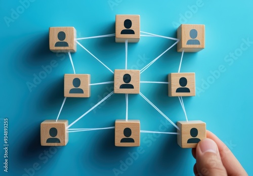 A hand connecting wooden blocks with user icons, illustrating networking and communication in a digital context.