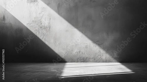 In a dimly lit room, a bright beam of light pierces through, illuminating the textured walls and floor, creating striking contrasts in shades of black and white, background