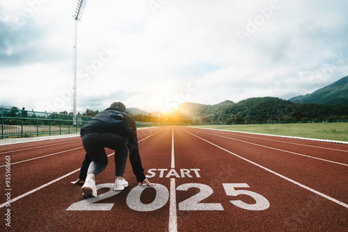 New year resolution 2025 concept. Word start 2025 written on athletics track and athlete woman runner preparing for new year at sunset for challenge and change. planning health and the goal to success