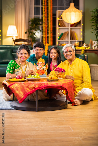 Indian family celebrating Ganesh Chaturthi, performing puja with traditional rituals and offerings