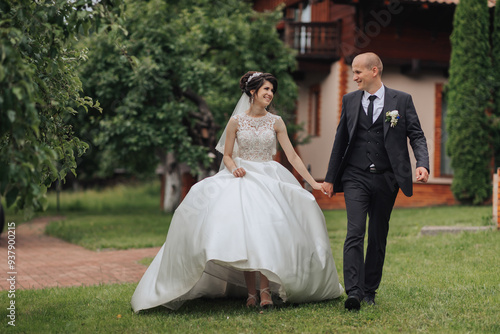 A bride and groom are walking down a grassy path. The bride is wearing a white dress and the groom is wearing a suit. They are holding hands and seem to be enjoying their time together