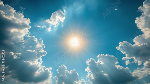 Bright sun shining through fluffy clouds on a clear blue sky