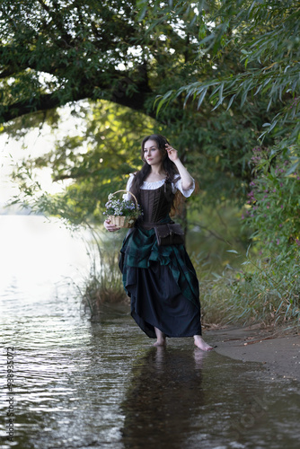 A girl in a corset on the bank of a summer river