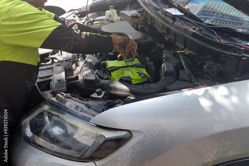 Closeup of technician replacing a worn out automobile car battery with a new battery.