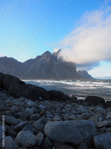 Rocky shoreline with waves crashing against the rocks under a cloudy sky, embodying the power and unpredictability of nature captured in a seawater setting.