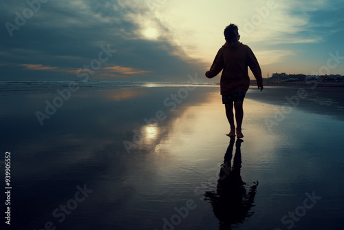 Silueta de niño en la playa con reflejos en el agua calma