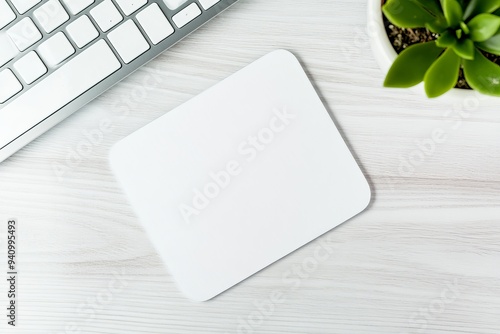 An elegant mousepad mockup with mouse, keyboard and an attractive potted succulent on top of a white wooden desk, a modern minimal workspace template for your product or design.