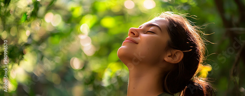 A young woman with a happy face breathing fresh air and smiling in a natural landscape.