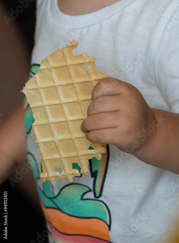  jedzony i trzymany w dłoni wafel przez małe dziecko.