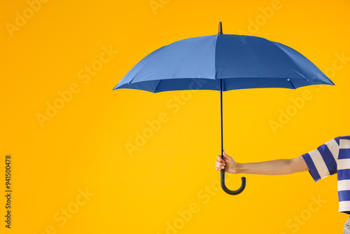 Woman with blue umbrella on yellow background, closeup