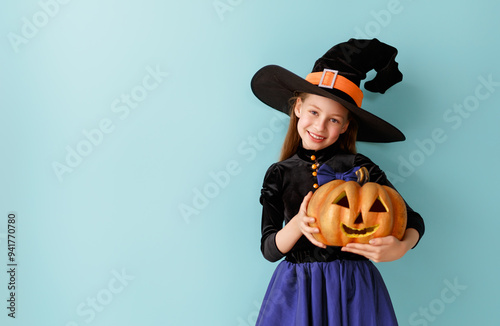 girl in witch costume with Halloween pumpkin