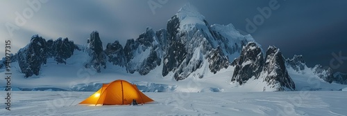 Tent illuminated against a dramatic mountain backdrop during a winter camping expedition