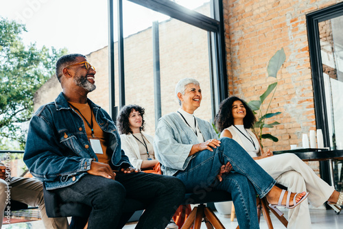 Happy group of adults watching and enjoying a meeting in a brightly lit room