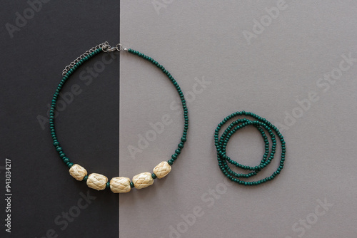 Straw and bead necklace and green beaded bracelet. Green beaded. Gray background