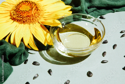 Sunflower oil with seeds and yellow sunflower flowers on light green background