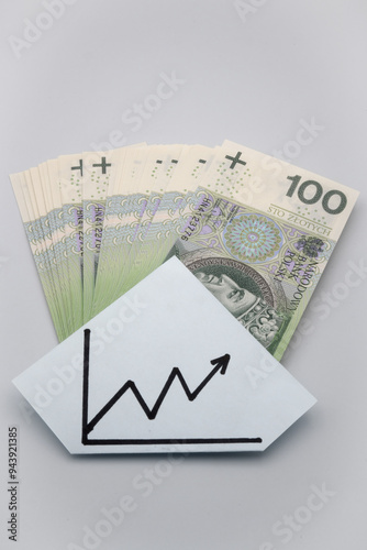 Polskie banknoty stu złotowe i wykres wzrostu.