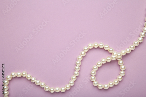 Elegant pearl necklace on purple background, top view. Space for text