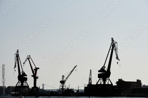 Profile of freight cranes in Gothenburg harbour, Sweden. Industrial Göteborg harbor shipyard with its tall derricks or crane. Goteborg port factory with high lifting derrick and Alvsborgsbron bridge