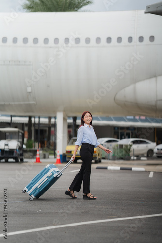 Ready for Takeoff: A young woman, radiating excitement, strides confidently across the airport tarmac, her blue suitcase trailing behind her, symbolizing the start of an adventure. 