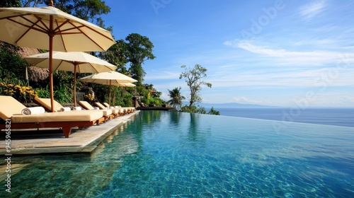 Elegant sun loungers and umbrellas by a clear blue swimming pool, a slice of holiday paradise in Indonesia.