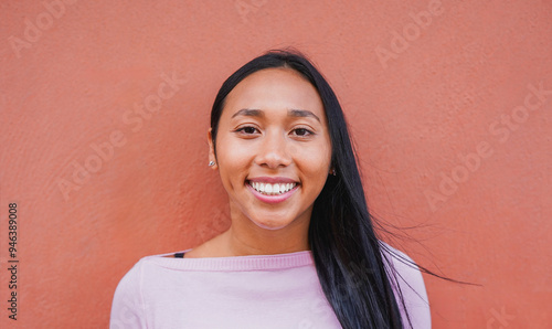 Portrait of native american woman smiling on camera with city wall in background - Indigenous girl outdoor