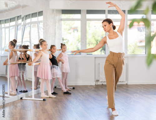 Female teacher dancer performing pirouette in front of class