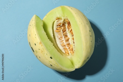 Cut fresh ripe honeydew melon on light blue background, top view