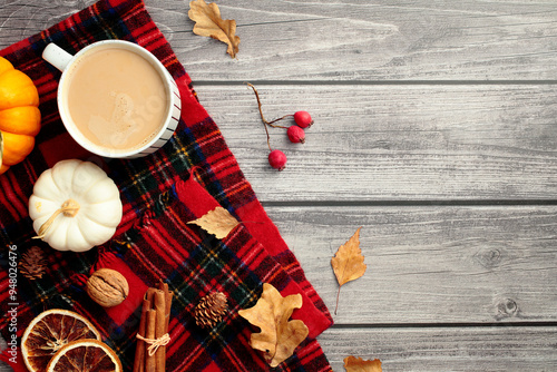 Cozy home desk table with red plaid, coffee cup, pumpkins, dry leaves, red berries. Autumn, fall concept. Hygge, nordic style. Flat lay, top view.