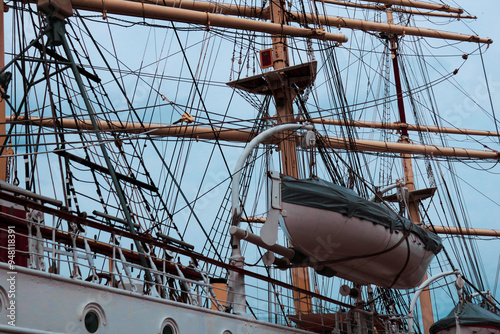 the mast of a ship with a boat