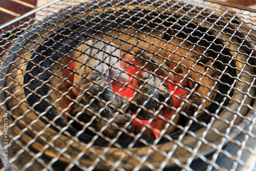 Close-up of metal grill on round brazier with charcoals in red fire at a resturant, South Korea