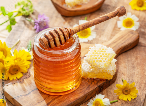 Natural organic honey in glass jar, honey dipper and honeycombs are near. Natural food background.