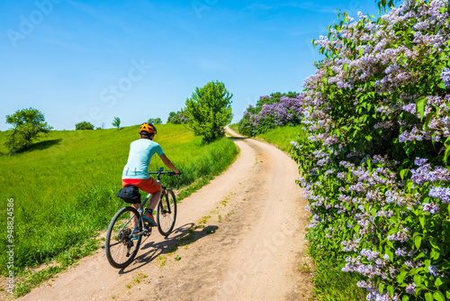 Woman cyclist riding bicycle on gravel forest road, Wigry National Park, Podlasie, Poland