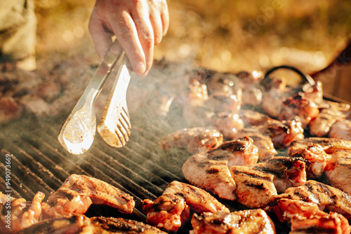 A hand expertly flipping juicy chicken wings on a sizzling grill, with delicious smoke rising in the background