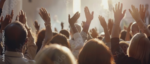 A crowd raises their hands in unison at a captivating event, illuminated by warm sunlight.