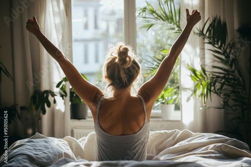 The concept of a new day and a joyful weekend is depicted by a woman stretching her hands in bed after waking up in the morning.