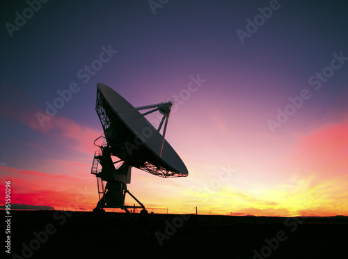 New Mexico, United States - August 1, 2002: Summer and sunset view of a satellite antenna of VLA(Very Large Array) on the desert against red glow in the sky