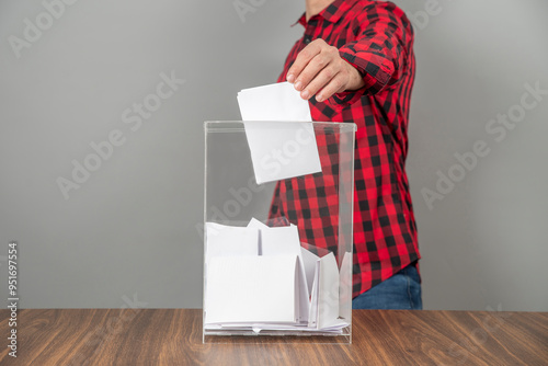 A voter casting a ballot into a ballot box on election day. Referendum, democracy, plebiscite concept