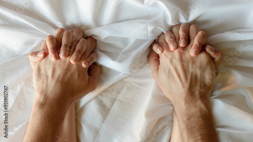 couple in love holding hands tightly while lying together in bed.