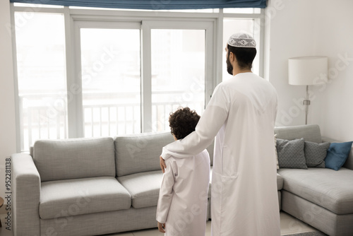 Caring Arabian father hugging kid, touching shoulder with love, support, looking at window away, thinking on family future, little son upbringing, real estate investment