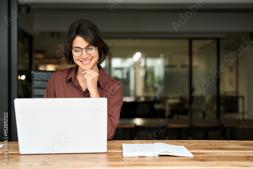 Young happy professional business woman executive working on computer technology in office, busy smiling businesswoman entrepreneur or hr manager using laptop sitting at work desk. Copy space for ads.