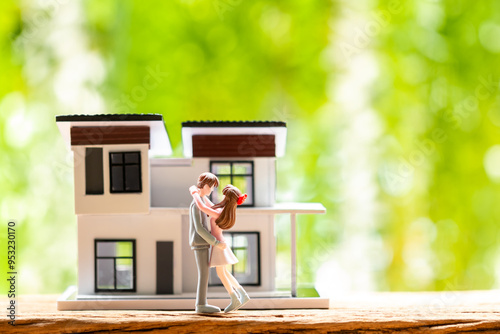 Couple Lover model hugging each other with love and house model on the wood on sunlight in the public park, Home sweet home or real estate for love and marriage of family to future concept.