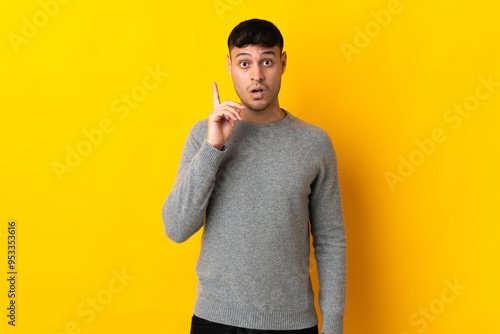 Young Colombian man isolated on yellow background intending to realizes the solution while lifting a finger up