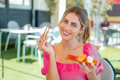 Young blonde woman holding sashimi at outdoors