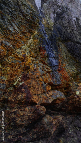 Beau fond et gros plan sur des rochers cotiers colorés blanc, rouge, beige et vert, entrée de grotte mystérieuse et intrigante, sur une plage des Astéries La Franca, cachette de trésor des pirates