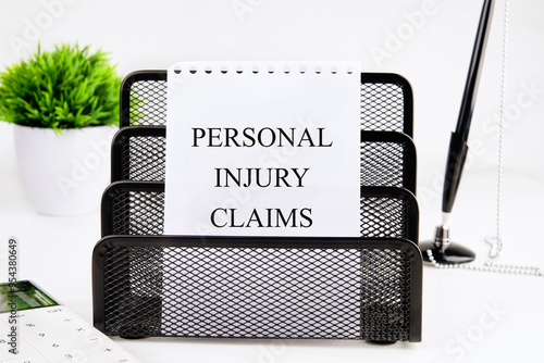 Legal services of lawyers for medical malpractice claims. PERSONAL INJURY CLAIMS words on a white sheet of paper in a stationery stand on a white background