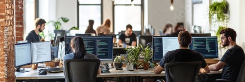 A group of developers engages in collaborative work at a tech startup, surrounded by computers and greenery, exemplifying a dynamic work environment